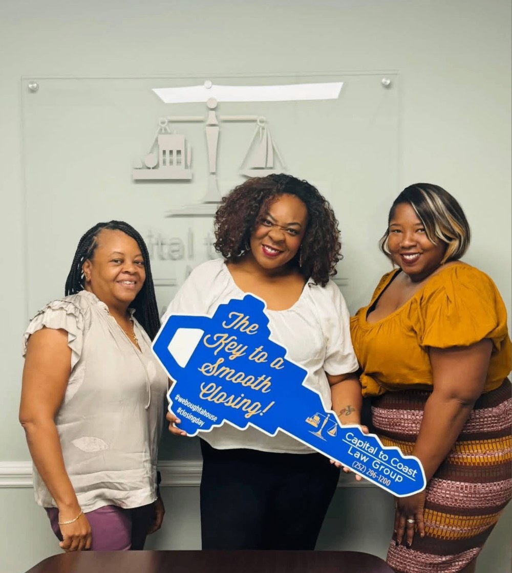 Clients holding a Key to a Smooth Closing sign