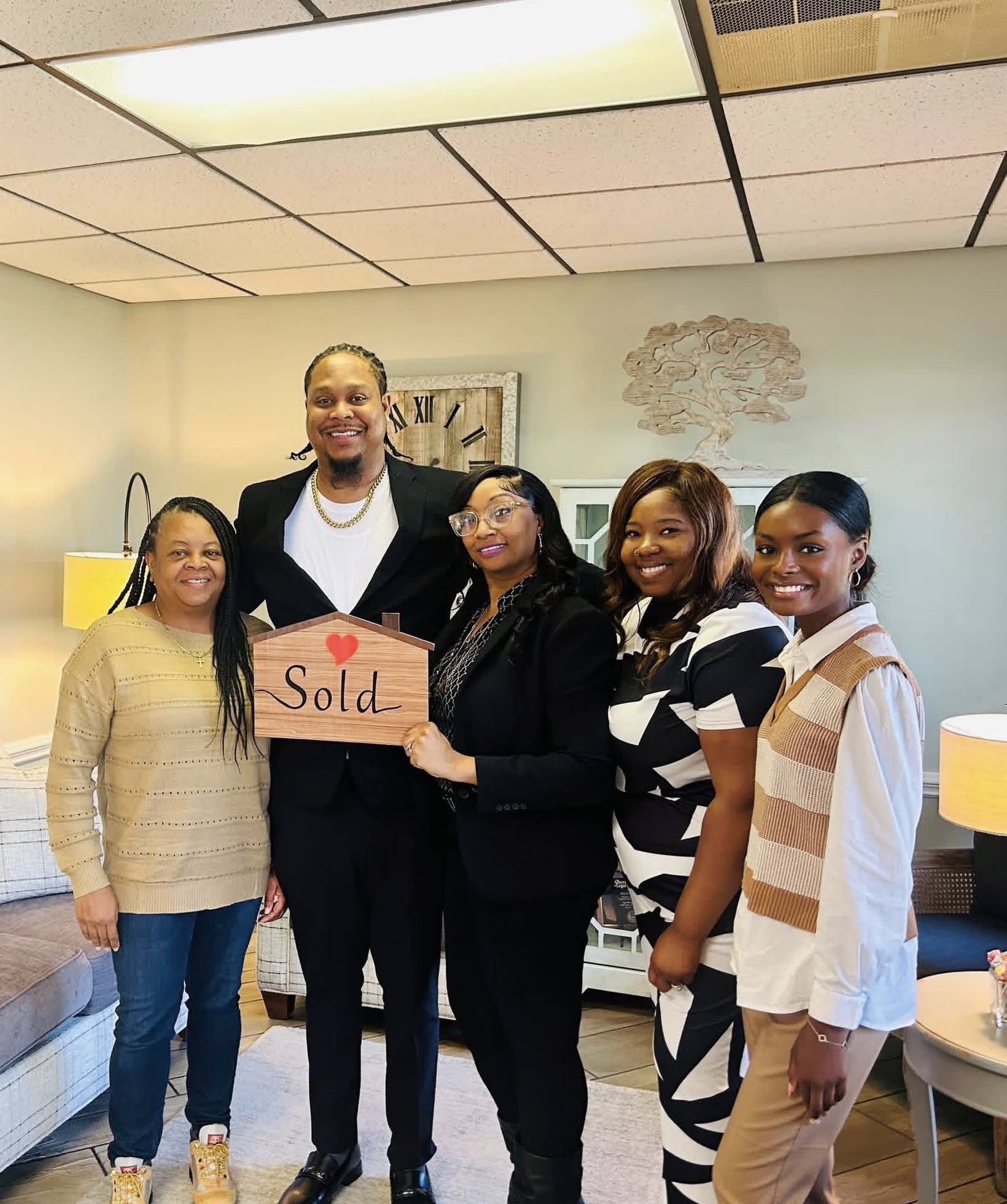 Family celebrating with a Sold sign after closing on their home