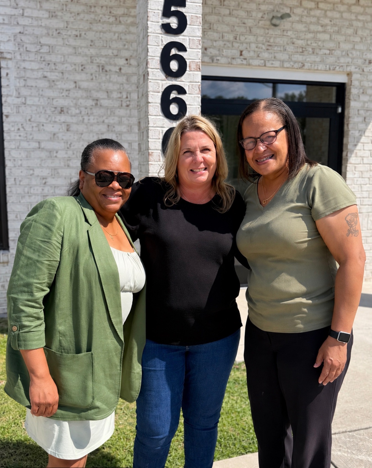 Three women celebrating together outside their new home